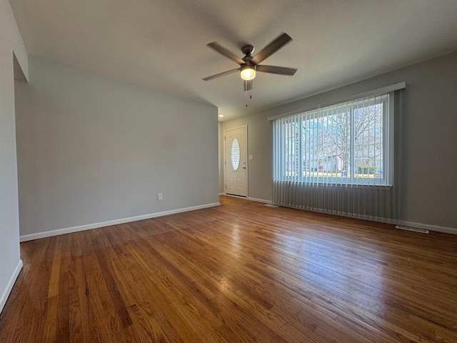 interior space with ceiling fan, wood finished floors, visible vents, and baseboards