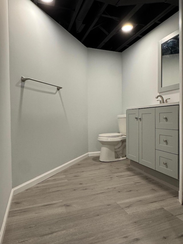 bathroom with baseboards, vanity, toilet, and wood finished floors