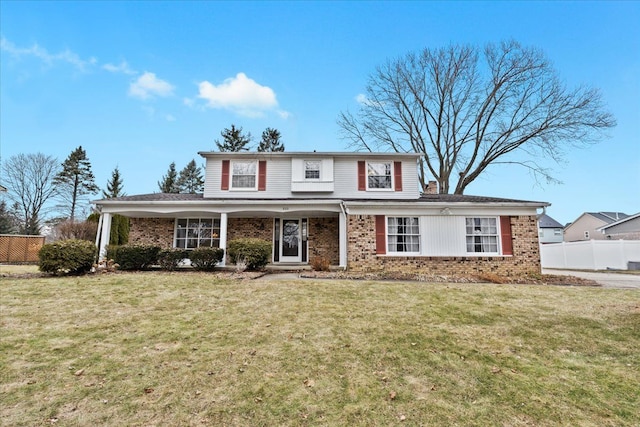 traditional-style home featuring brick siding, fence, and a front lawn