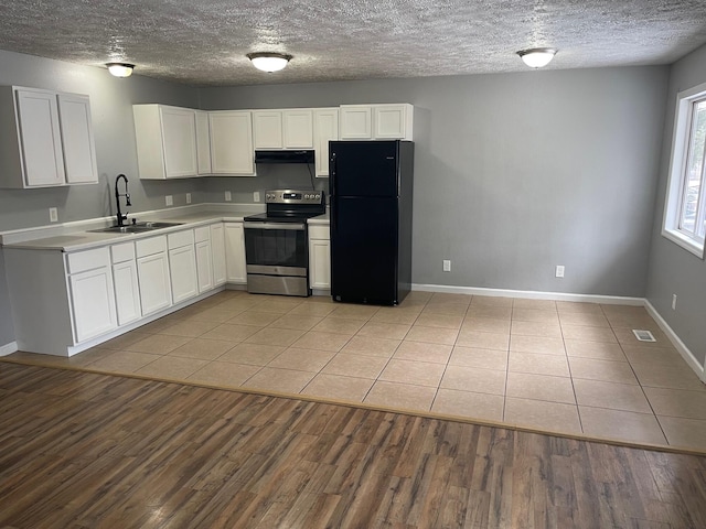 kitchen with stainless steel electric range oven, freestanding refrigerator, a sink, light wood-type flooring, and under cabinet range hood