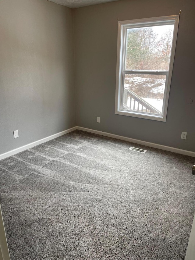 spare room featuring baseboards, visible vents, and carpet flooring