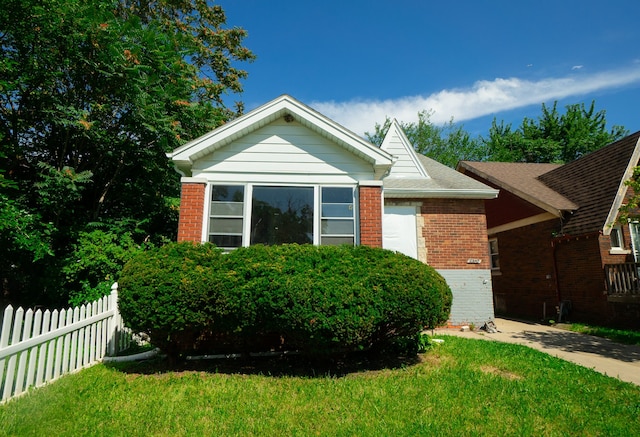 view of front of house with a front yard, brick siding, and fence