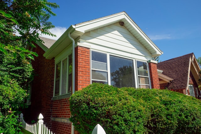 view of side of property with fence and brick siding