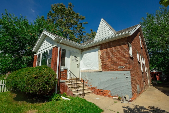 view of front of property featuring entry steps, brick siding, and fence