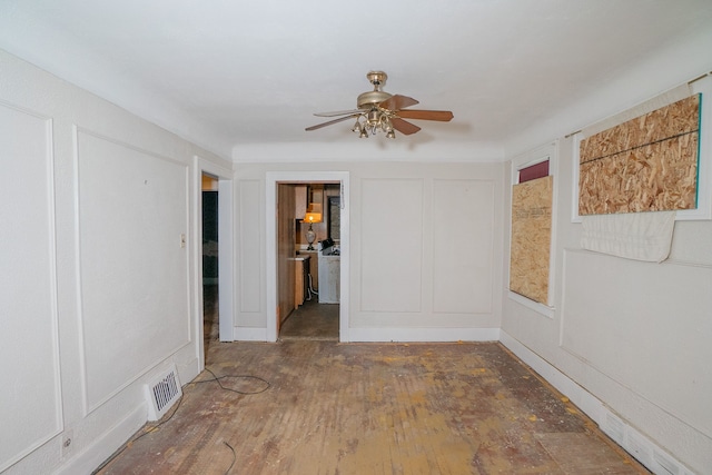 unfurnished room featuring wood-type flooring, visible vents, a decorative wall, and a ceiling fan