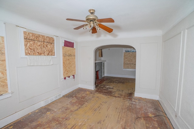 unfurnished room with visible vents, arched walkways, baseboards, hardwood / wood-style flooring, and ceiling fan