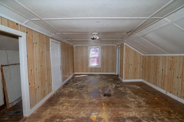 additional living space featuring lofted ceiling, wooden walls, and baseboards