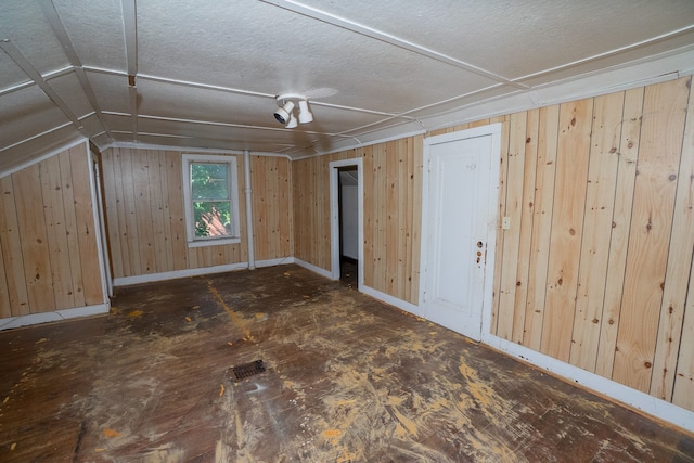 bonus room with a textured ceiling, wood walls, vaulted ceiling, and baseboards