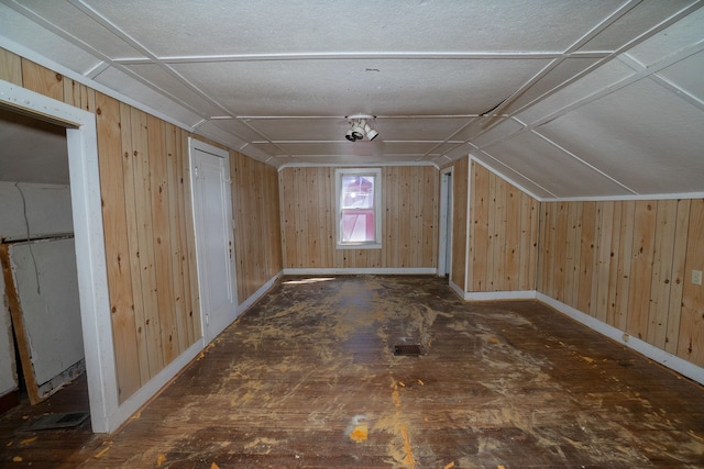 bonus room featuring vaulted ceiling, wooden walls, and baseboards