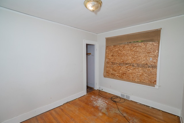 spare room featuring ornamental molding, visible vents, baseboards, and wood finished floors
