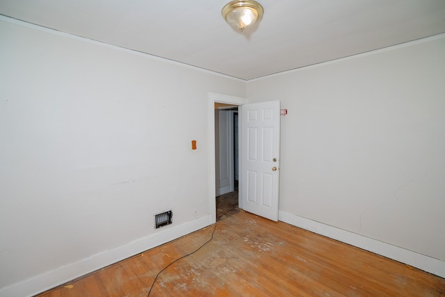 unfurnished room with ornamental molding, wood finished floors, visible vents, and baseboards