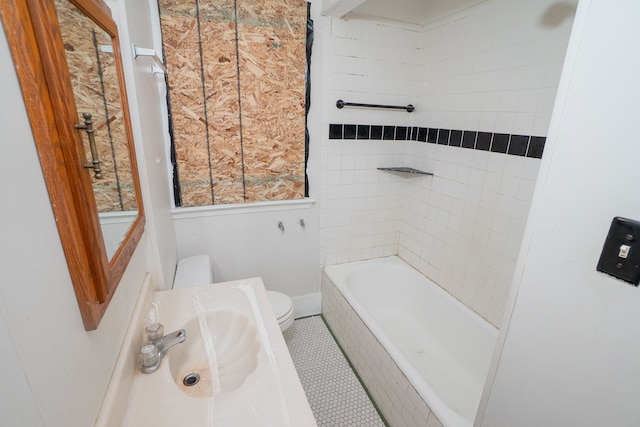 full bathroom with tile patterned flooring, a sink, tiled shower / bath, and toilet