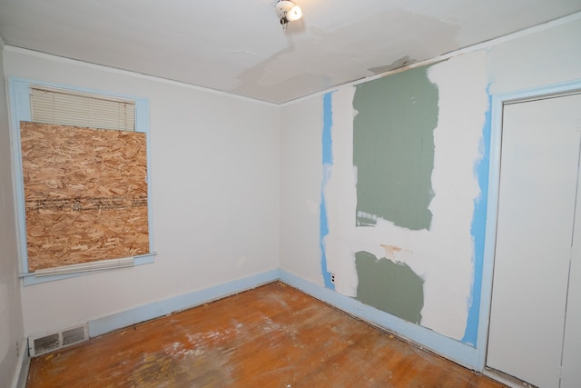 spare room with visible vents, baseboards, and wood finished floors