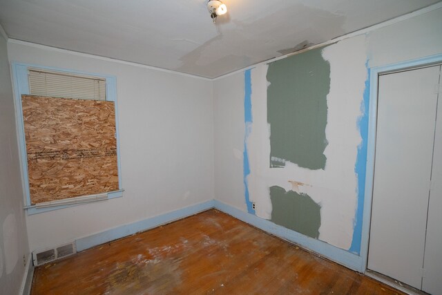 spare room featuring wood finished floors, visible vents, and baseboards