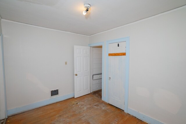 unfurnished bedroom featuring baseboards, visible vents, wood finished floors, and ornamental molding