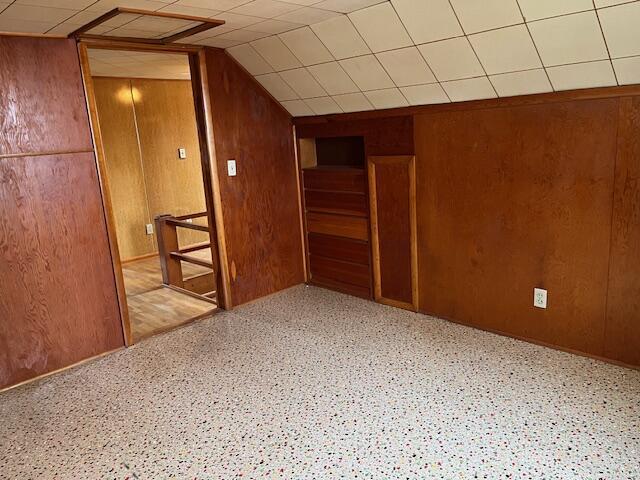 bonus room with vaulted ceiling and wood walls