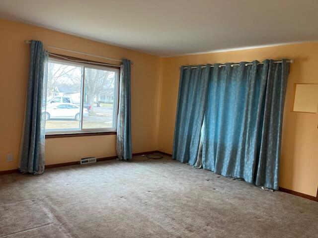 spare room featuring baseboards, visible vents, and carpet flooring