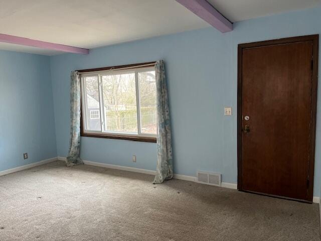 empty room featuring baseboards, carpet, visible vents, and beam ceiling