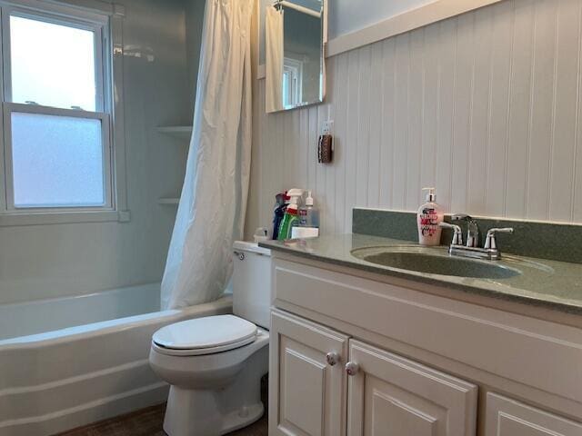 bathroom featuring toilet, shower / bath combo with shower curtain, and vanity