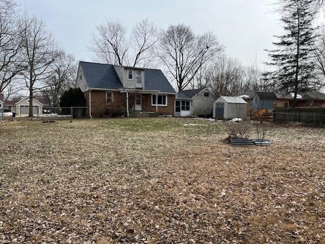 back of house with brick siding, a shed, fence, and an outbuilding