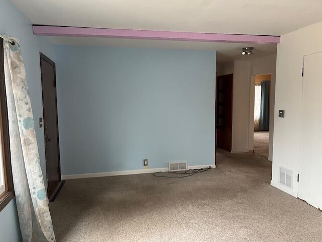 carpeted spare room featuring visible vents and baseboards