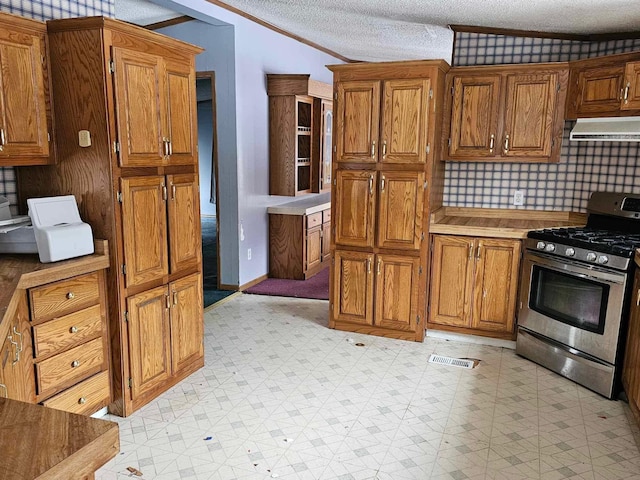 kitchen featuring crown molding, light floors, brown cabinetry, ventilation hood, and gas range