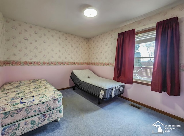 carpeted bedroom featuring wallpapered walls, visible vents, and baseboards