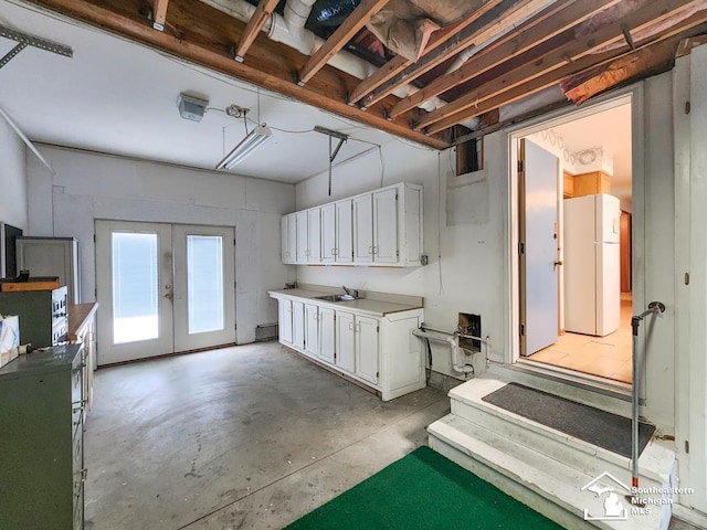 interior space featuring a sink, a garage, french doors, and freestanding refrigerator