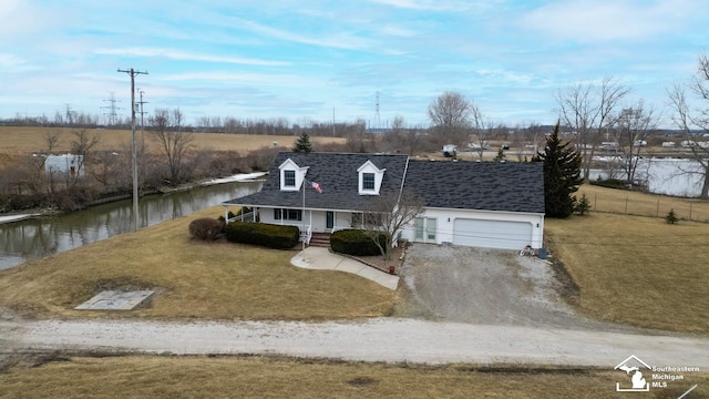 cape cod home with roof with shingles, covered porch, an attached garage, a front yard, and driveway