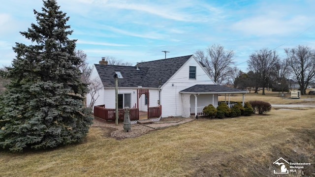 back of house featuring roof with shingles, a lawn, a chimney, and a wooden deck