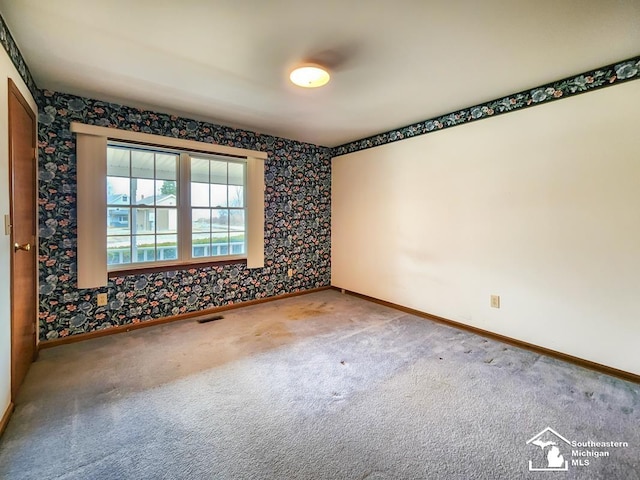 empty room with carpet floors, baseboards, and visible vents