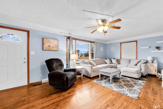 living area with a textured ceiling, wood-type flooring, visible vents, and a ceiling fan