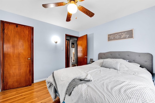 bedroom featuring ceiling fan, light wood-style flooring, and baseboards