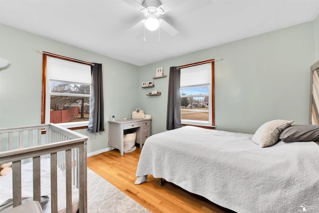 bedroom with multiple windows, wood finished floors, a ceiling fan, and baseboards