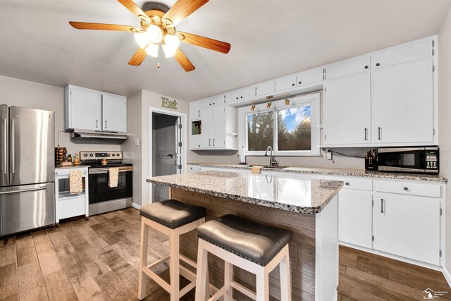 kitchen featuring white cabinets, stainless steel appliances, light wood-style flooring, and under cabinet range hood