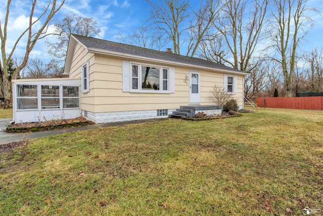 view of front of property with a sunroom, fence, a chimney, and a front lawn