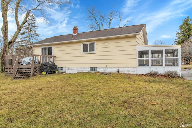 rear view of property featuring a deck, a sunroom, a yard, and a chimney