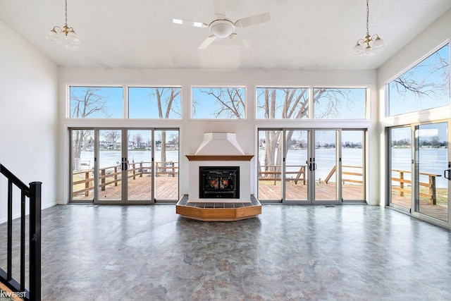 unfurnished living room featuring stairs, a high ceiling, a tiled fireplace, and french doors