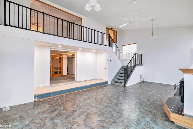 unfurnished living room with stairway, a towering ceiling, and baseboards