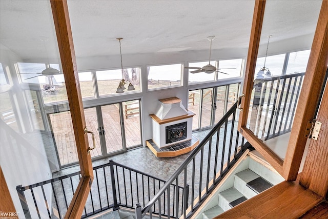 stairs with a ceiling fan, a wealth of natural light, and a towering ceiling