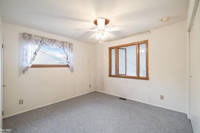 carpeted spare room featuring ceiling fan, visible vents, and baseboards