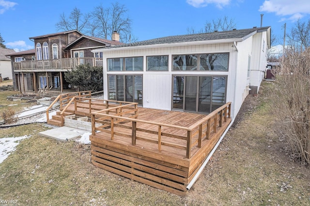 rear view of property featuring a sunroom, a chimney, and a wooden deck