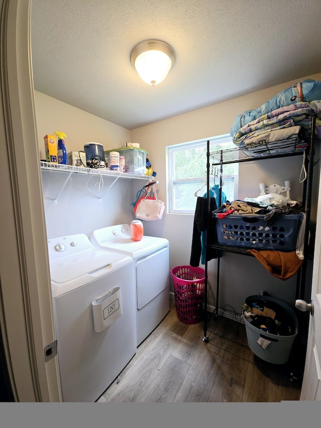 laundry room featuring laundry area, a textured ceiling, washer and clothes dryer, and wood finished floors