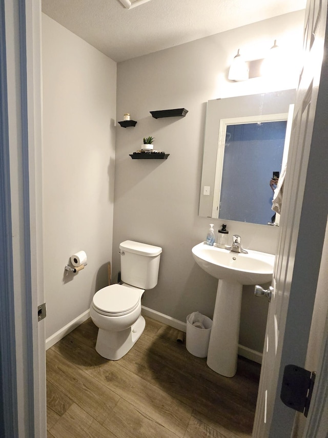 bathroom featuring a sink, wood finished floors, toilet, and baseboards