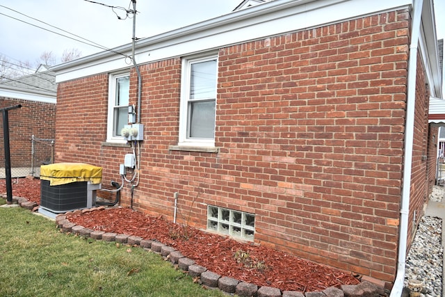 view of side of property with brick siding, fence, and central AC unit