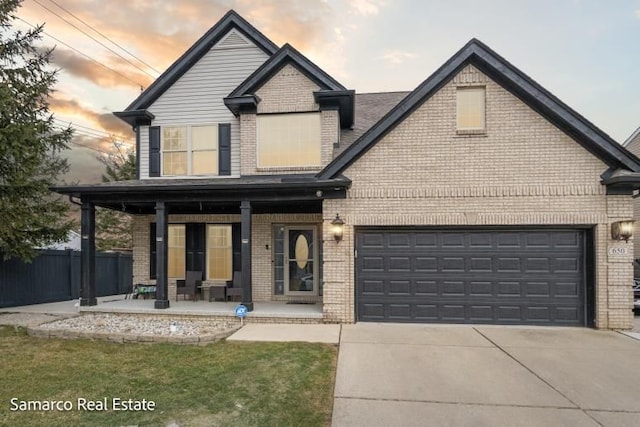 view of front of house featuring a garage, covered porch, brick siding, fence, and driveway