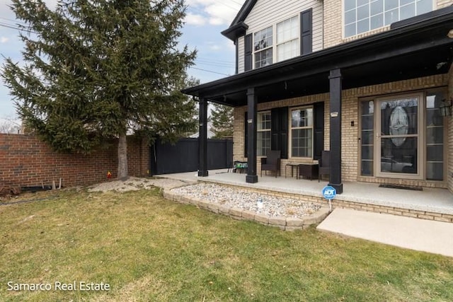 exterior space featuring a porch, a yard, brick siding, and fence