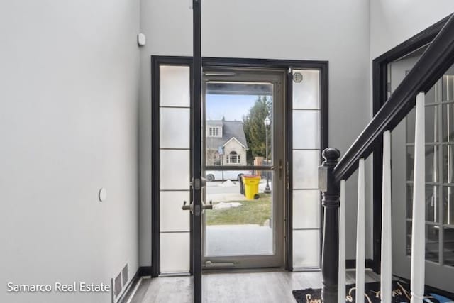 entryway featuring wood finished floors, visible vents, and stairs