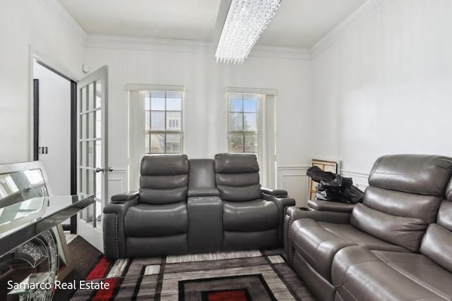 cinema room featuring a notable chandelier, a decorative wall, a wainscoted wall, and crown molding