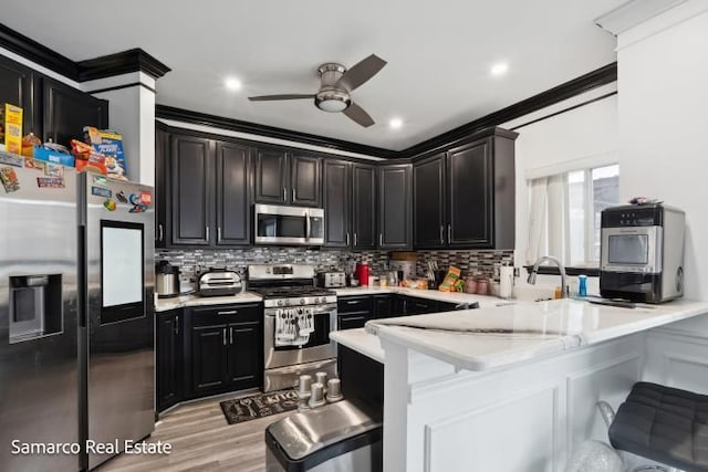 kitchen with a peninsula, light countertops, ornamental molding, appliances with stainless steel finishes, and tasteful backsplash